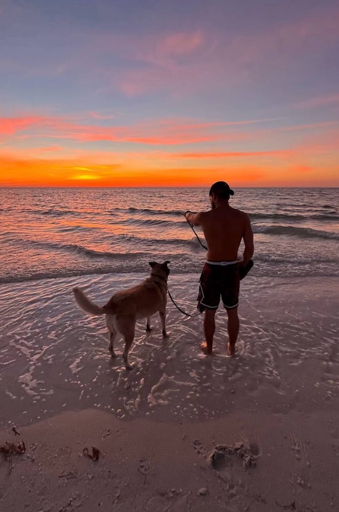Coach Ty Alexander at sunset on a St. Petersburg beach with his dog Lola.